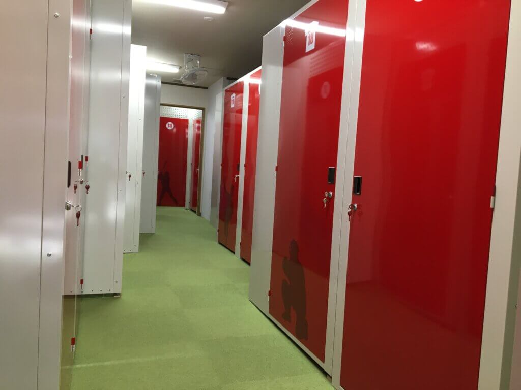 プラスルーム広島マツダスタジアム前店の室内通路と赤いトランクルーム収納庫