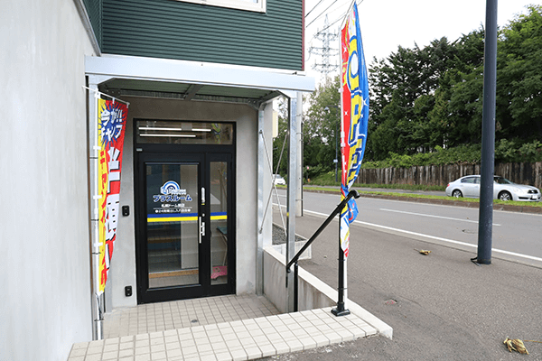 トランクルーム札幌ドーム前福住店の入口。のぼり旗が立つガラス扉のエントランス