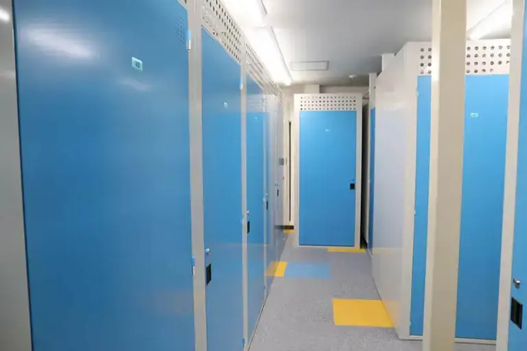 プラスルーム札幌石山店の屋内型トランクルーム内部、青い扉が並ぶ収納ボックスの通路