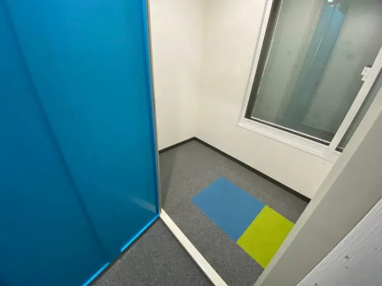 屋内型トランクルーム札幌豊平公園店の個室内部。青い扉と窓のある収納スペース